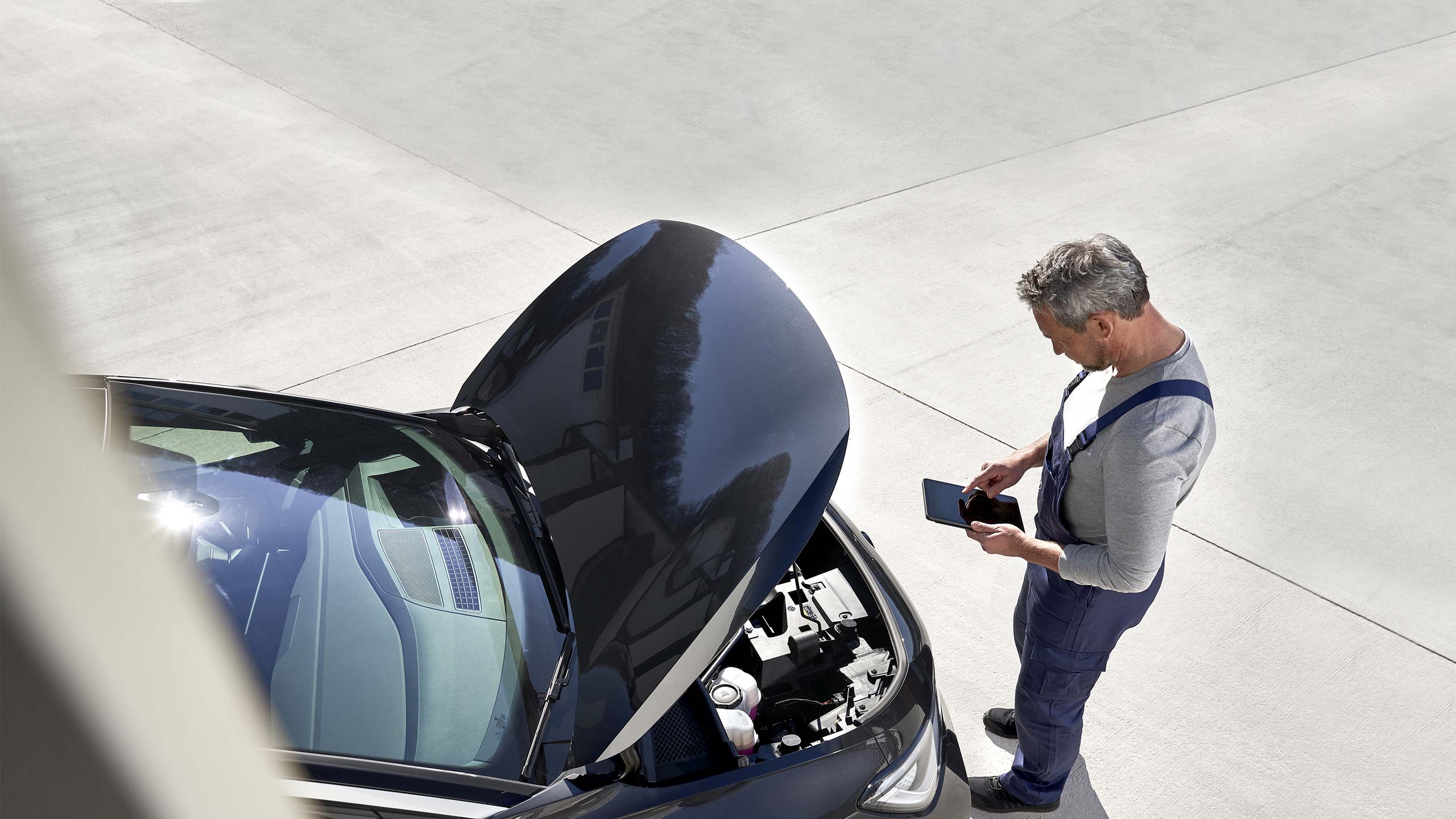 Un meccanico Volkswagen Service ispeziona l'interno del cofano di un'auto Volkswagen.